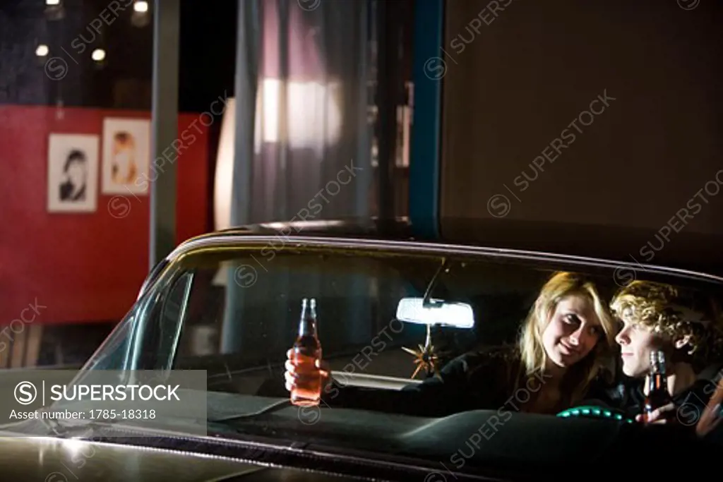 Young couple on a date drinking in a car