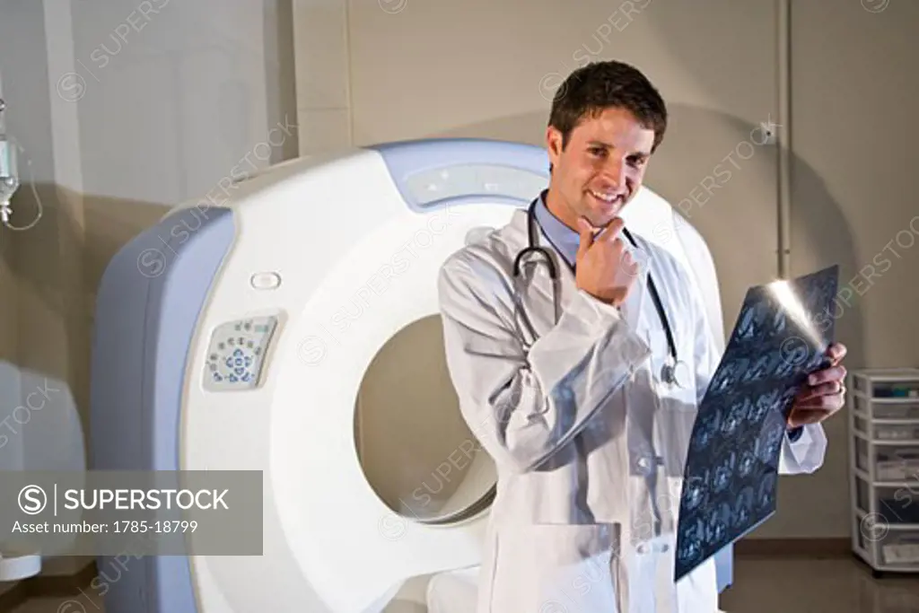 Radiologist holding test results next to CT scanner