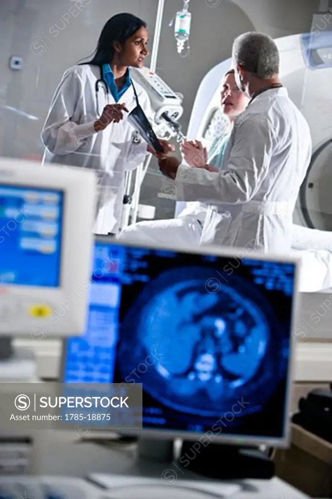 Radiologists looking at test results with patient near CT scanner