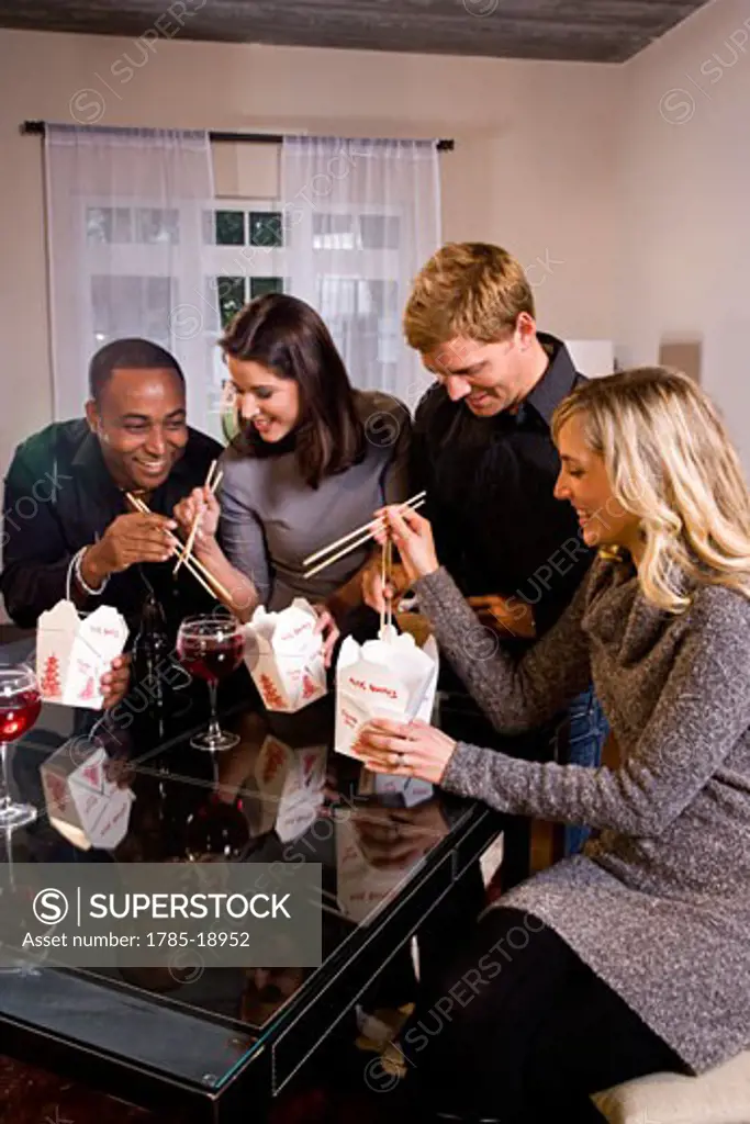 Multi-ethnic couples eating Chinese take-out in modern loft