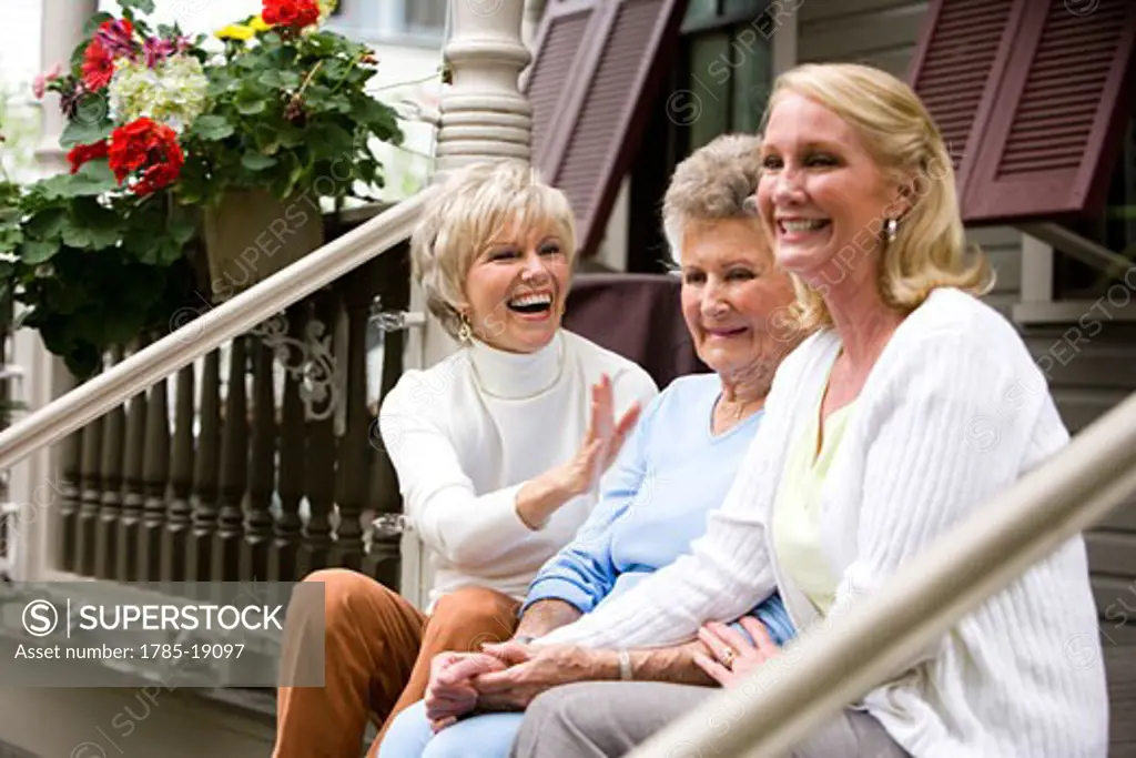 Elderly woman and adult daughters on front porch of house