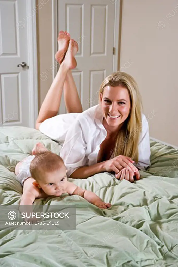 Young mother and 6 month old baby lying on bed