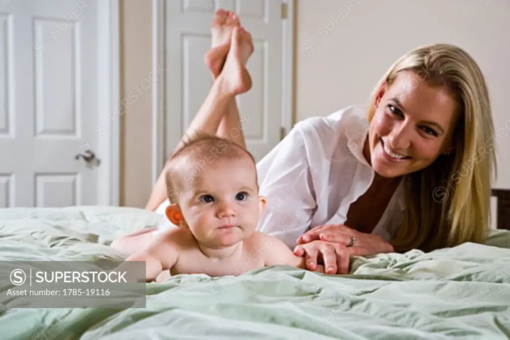 Young mother and 6 month old baby lying on bed