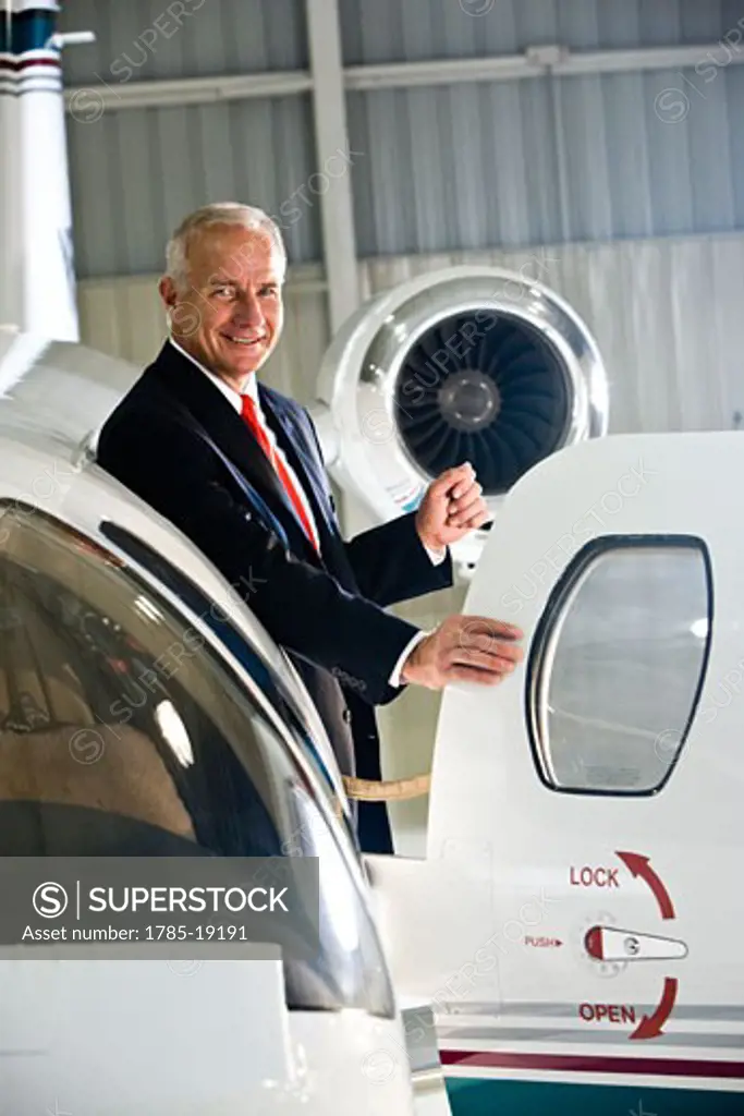 Businessman standing at doorway of corporate jet