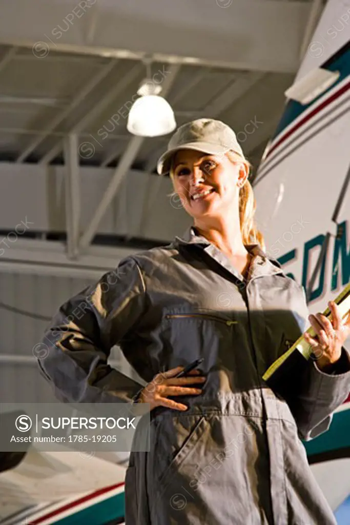 Female airplane mechanic in hangar next to private jet