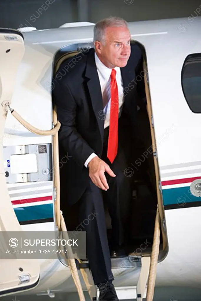 Middle-aged businessman stepping off corporate jet