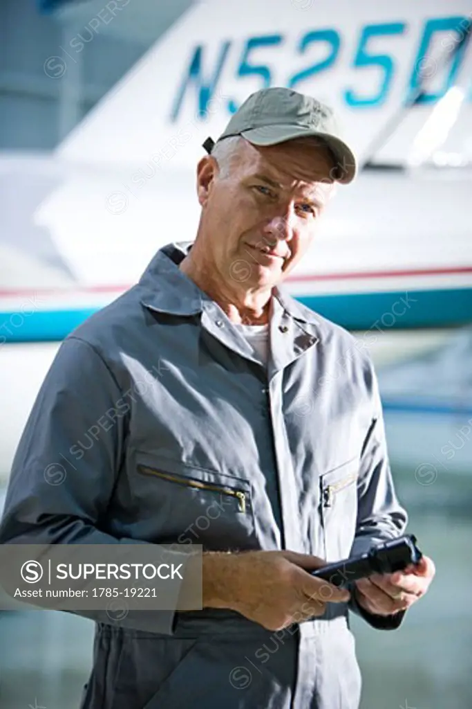 Airplane mechanic holding flashlight standing next to private jet