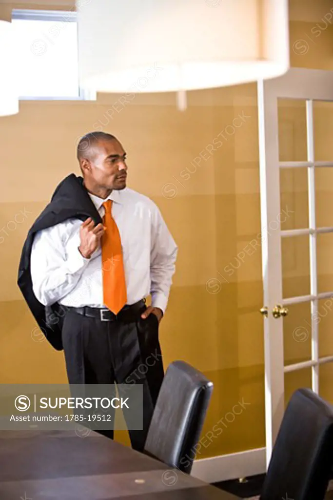 Serious businessman standing in office with jacket over shoulder