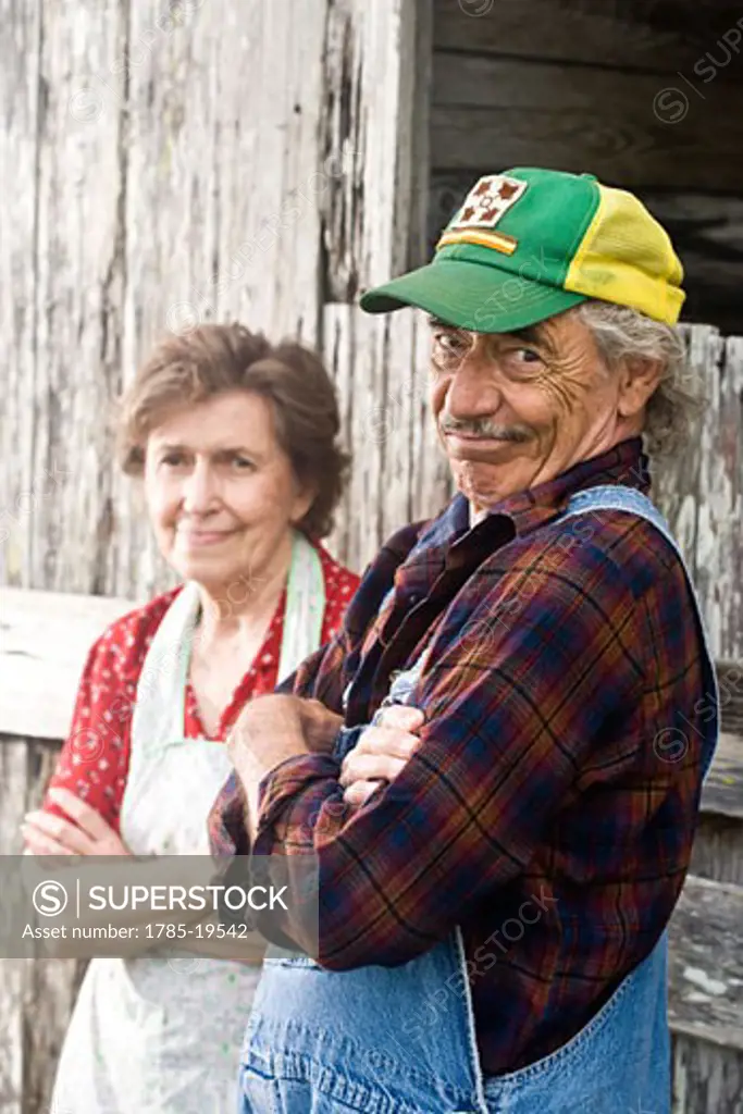 Senior couple standing outside weathered barn