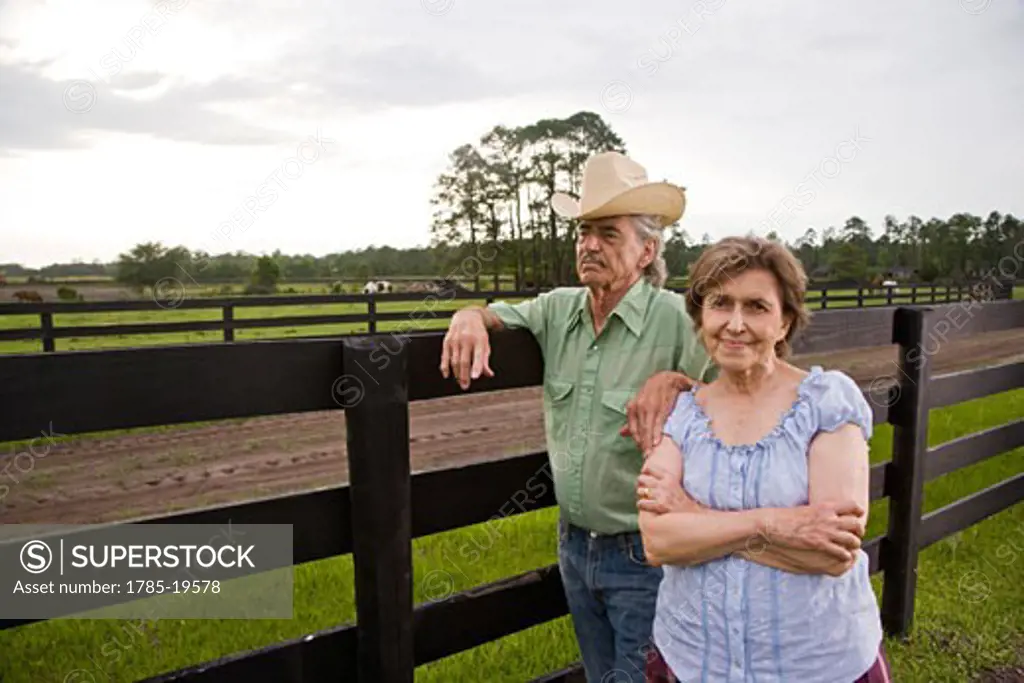 Senior couple standing on ranch near fence