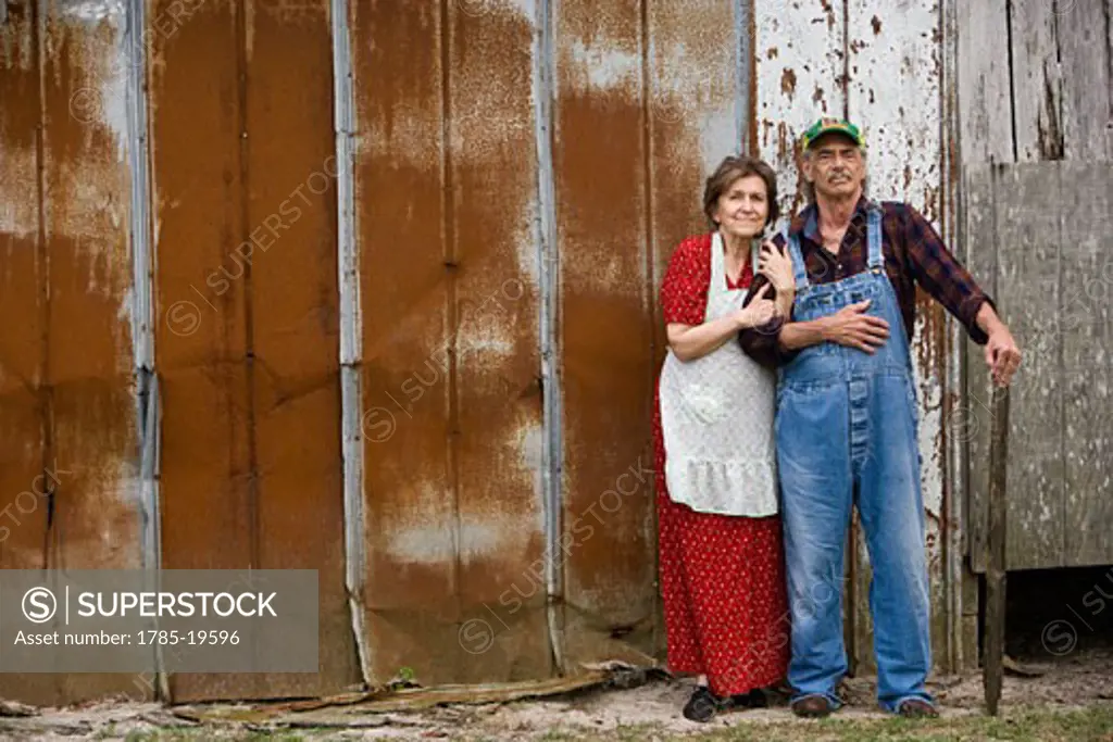 Senior couple standing outside weathered barn