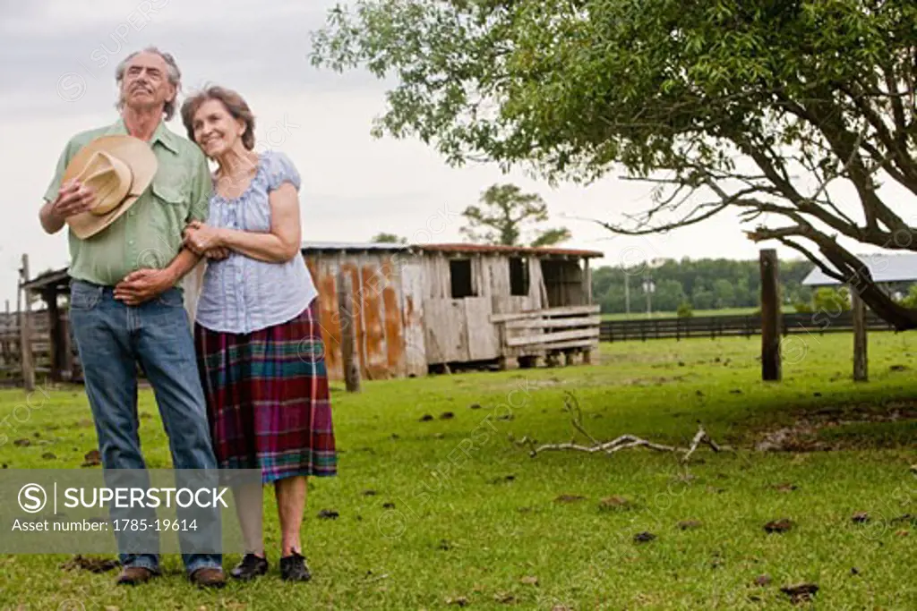 Senior couple standing together outside old farmhouse