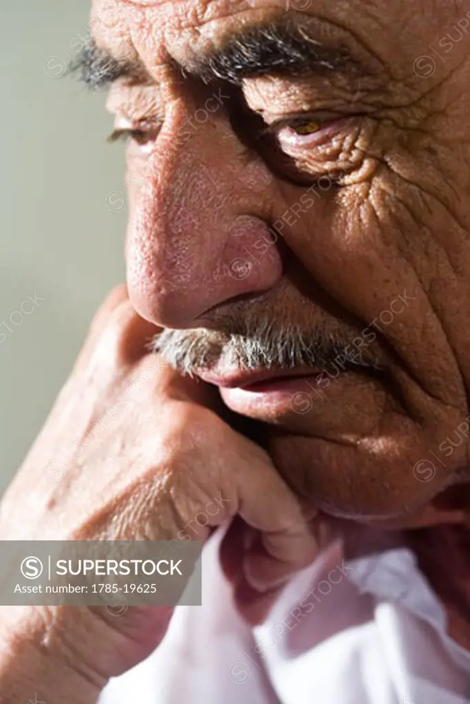 Close-up of depressed senior man with hand on chin