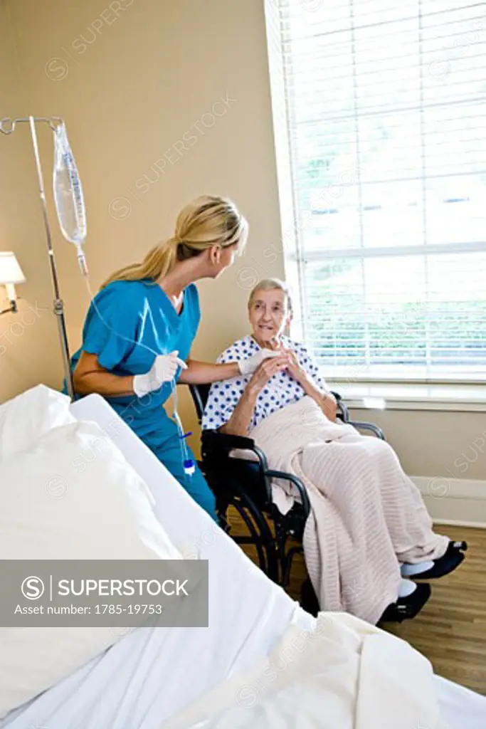 Nurse and senior woman in wheelchair in hospital room
