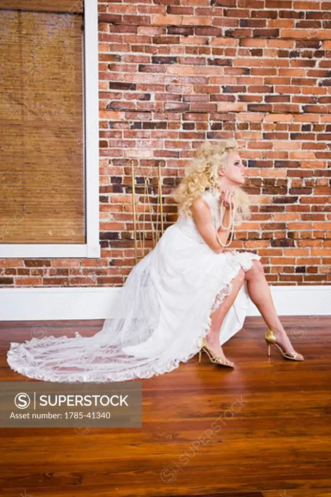 Young blonde woman posing in white gown