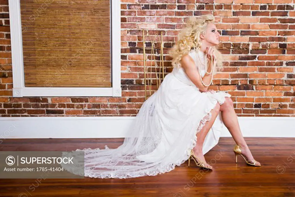 Young blonde woman posing in white gown