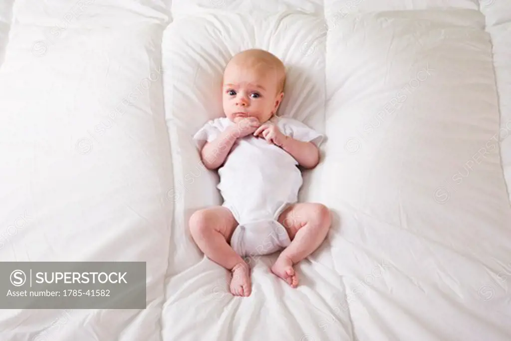 Newborn baby in onesie lying on soft white blanket