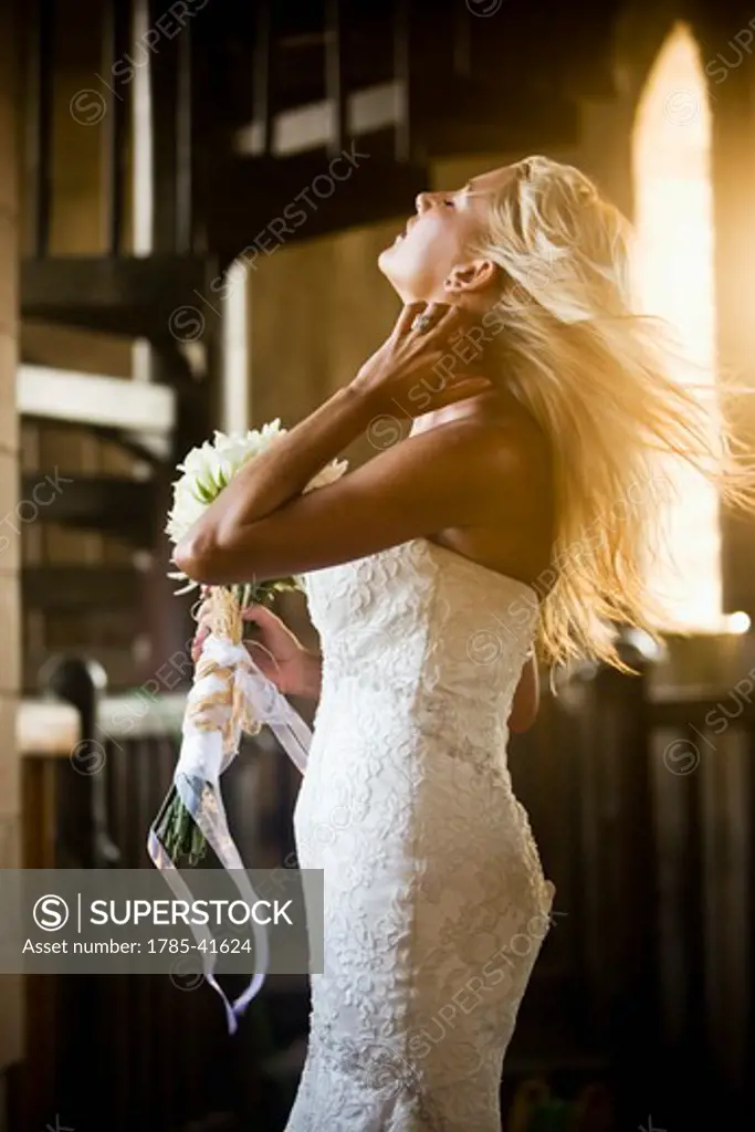 Young bride with bouquet enjoying wind blowing through hair