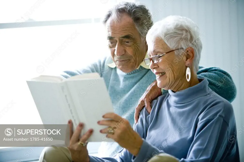 Senior couple sitting on bed reading book