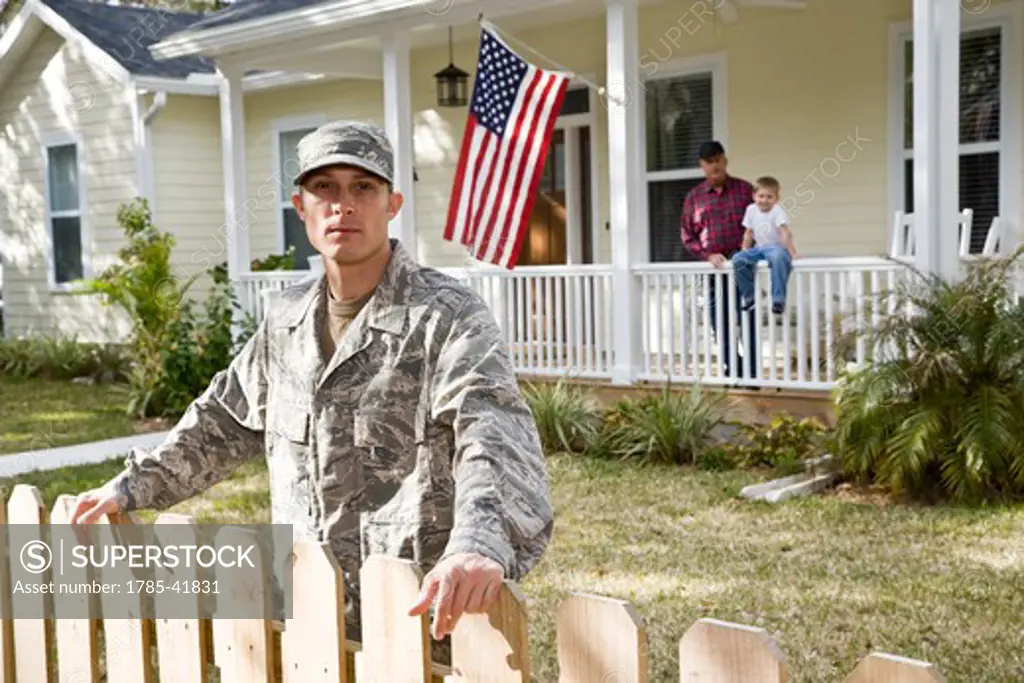 Military man, family in background by American Flag