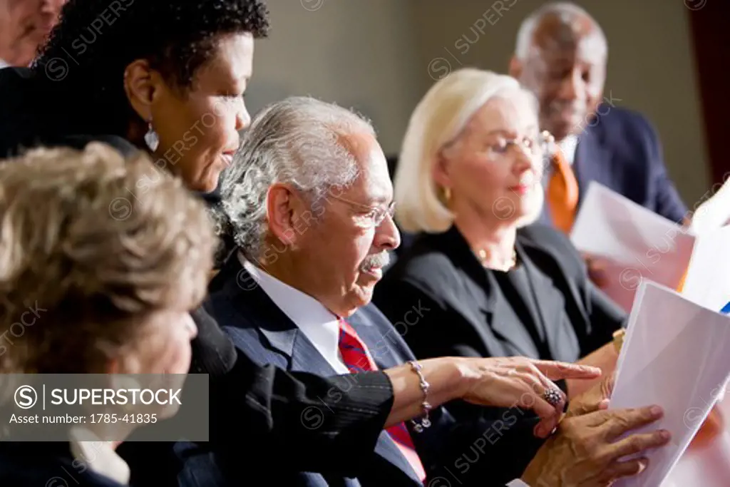 Multi-ethnic senior management meeting, pointing to report