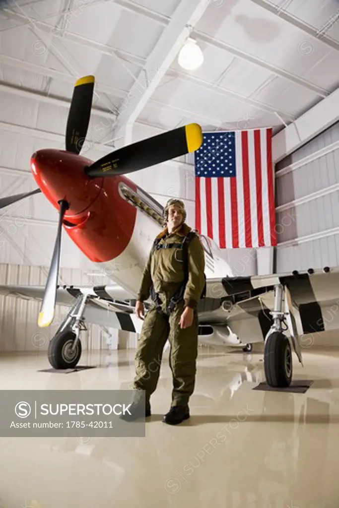Pilot with vintage fighter plane in hangar