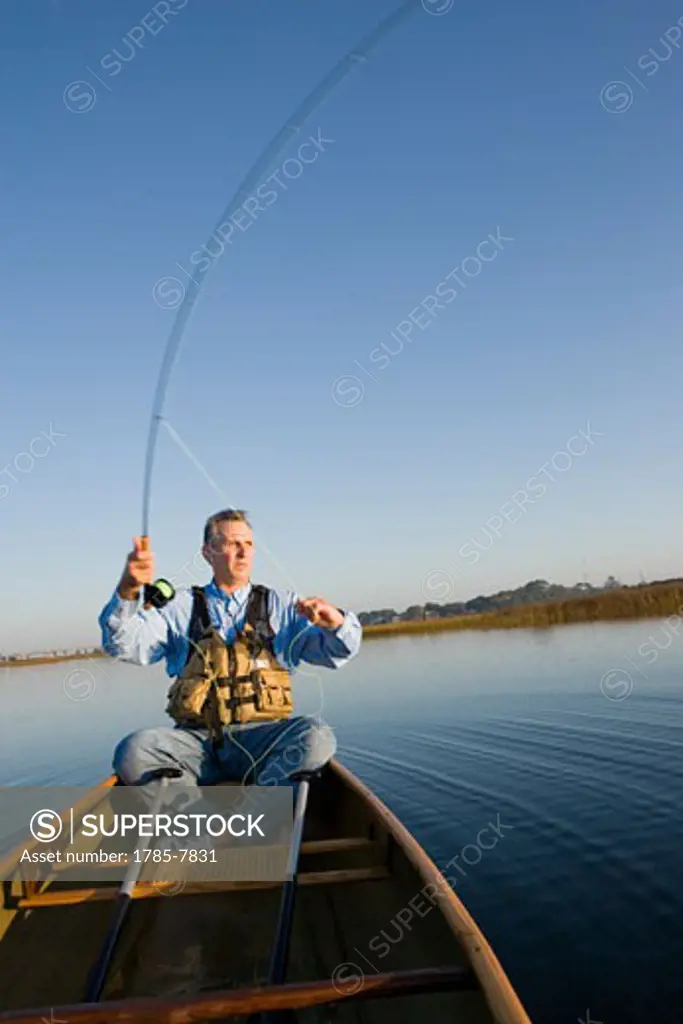 Middle-aged man fly fishing in canoe on Florida Intracoastal Waterway