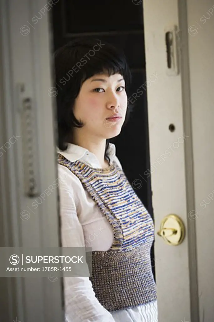Portrait of a young Asian woman standing at front door