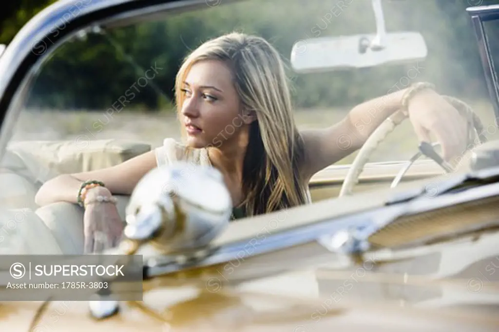 Young woman sitting in antique convertible car