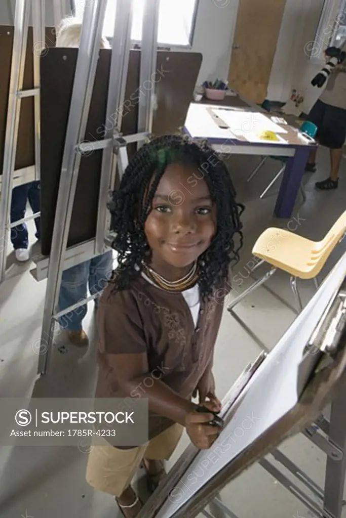 Portrait of a girl drawing on an easel in art class