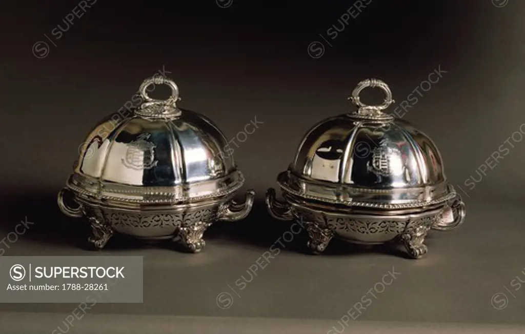 Silversmith's Art, England 19th century. Robert Garrard, Pair of silver covered dishes, engraved with a coat of arms, with plated with silver and pierced stands, curl-shaped stems, moulded handles and dome-shaped cover. London, 1821.