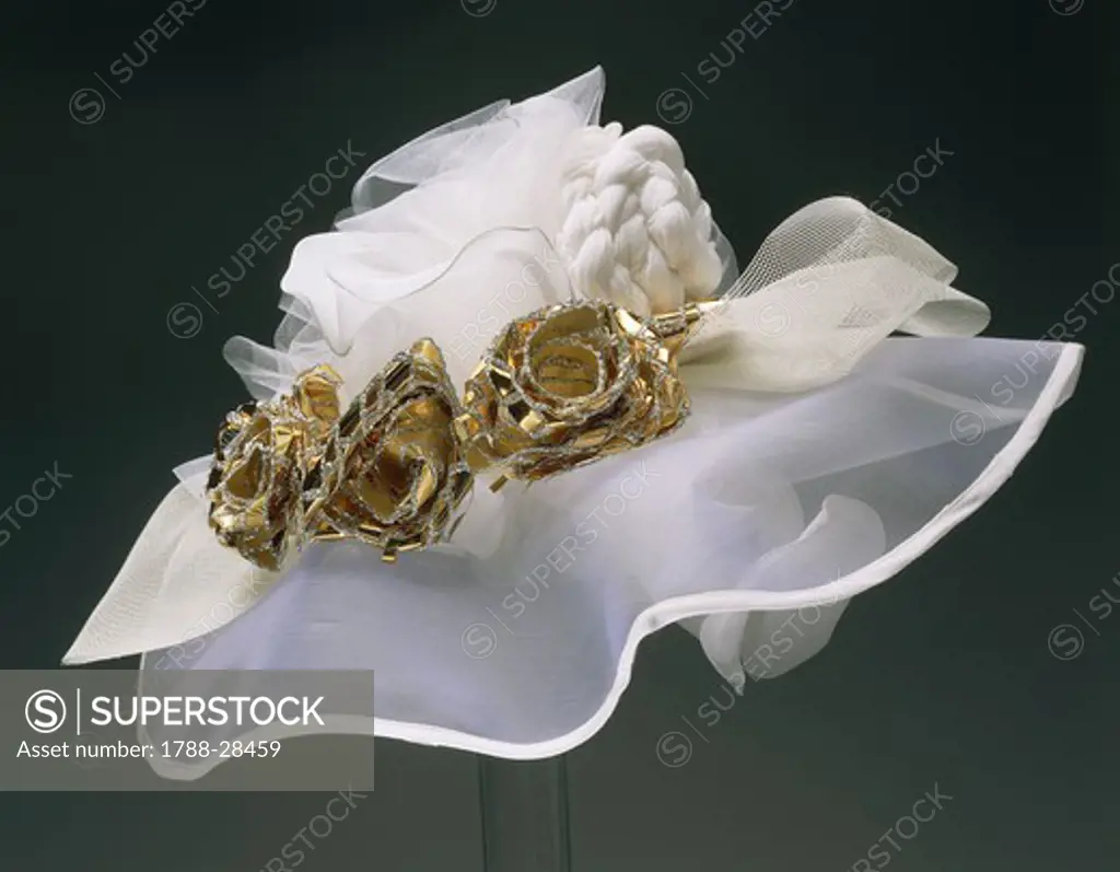 Fashion, Italy, 20th century. Ceremonial brim hat in white organza ornamented with three golden paper roses.
