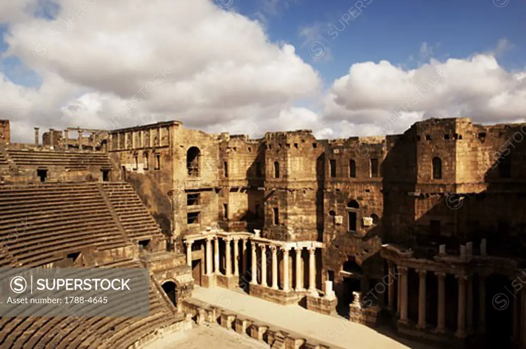 Syria - Bosra. Ancient Bosra. UNESCO World Heritage List, 1980. Roman theater, AD 2nd century. City walls built to lean on theater stage rear columns