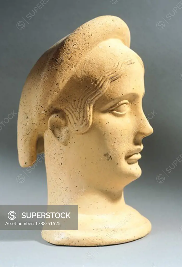 Female head wearing bonnet, clay votive statue ifrom Carseldine, Abruzzo, Italy. Italic Civilization, 4th-3rd Century BC.