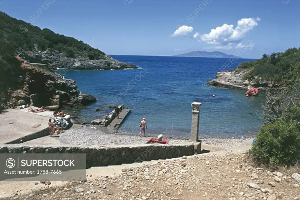 Tourists sunbathing near a cove, Maestra Cove, Giannutri Island, Tuscany, Italy