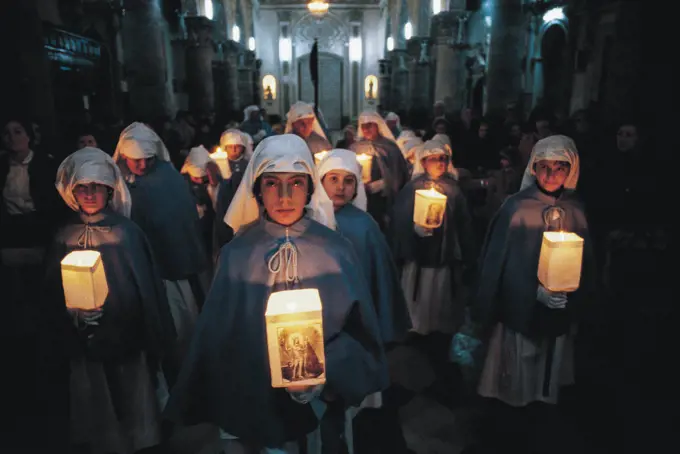 Hooded members of a brotherhood holding flambeaux candles, Holy Week, Enna, Sicily, Italy.