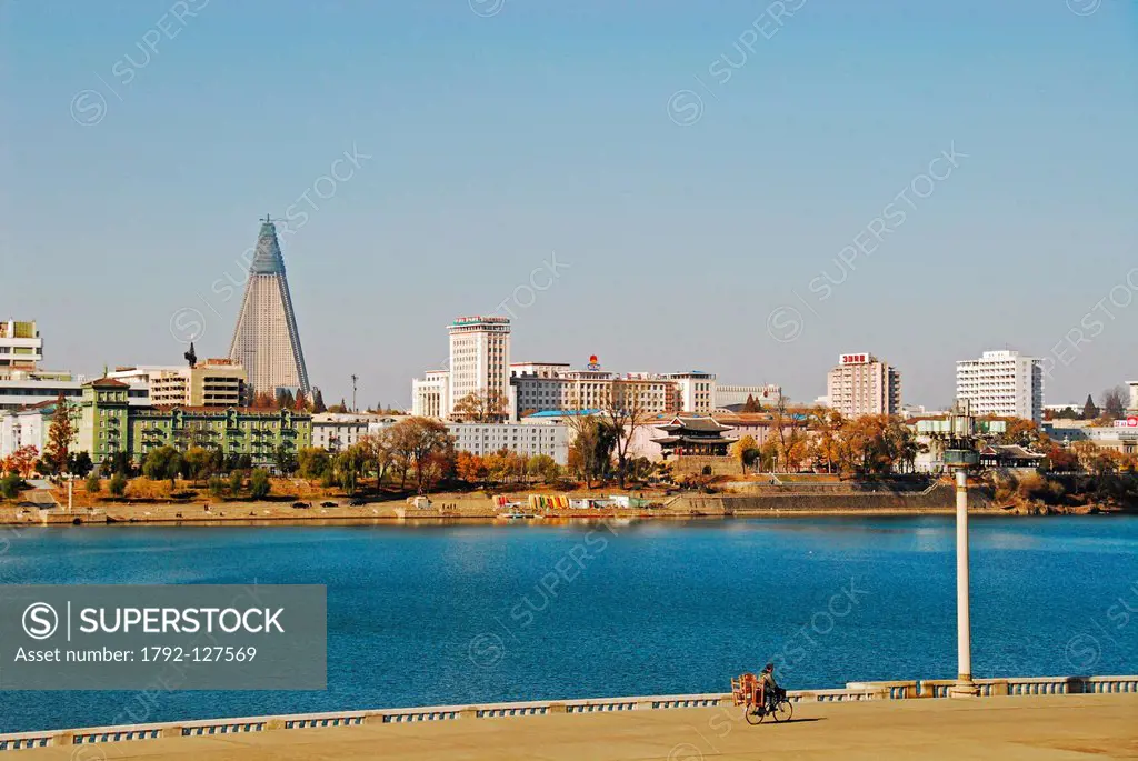 North Korea, Pyongyang, adult riding a bicycle to the river