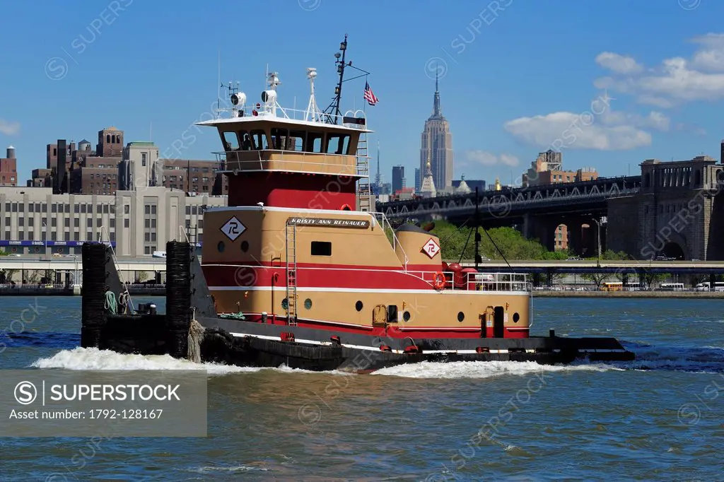 United States, New York City, Manhattan, tug operating on the East River, Manhattan Bridge and Empire State Building in the back