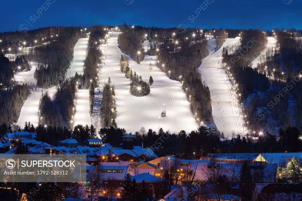 Canada, Quebec province, Laurentians region, St Sauveur, the city and in the background the ski slopes lit at night