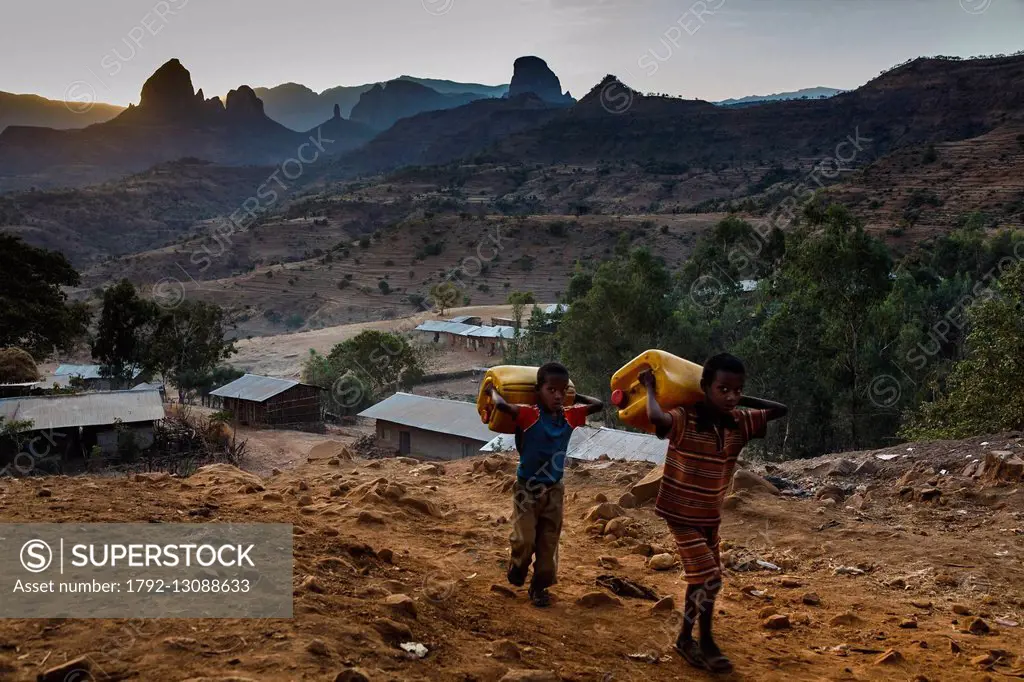Ethiopia, Amhara region, Adi Arkay, Simien Mountains National Park listed as World Heritage by UNESCO, boys carrying water container at the sunrise on...