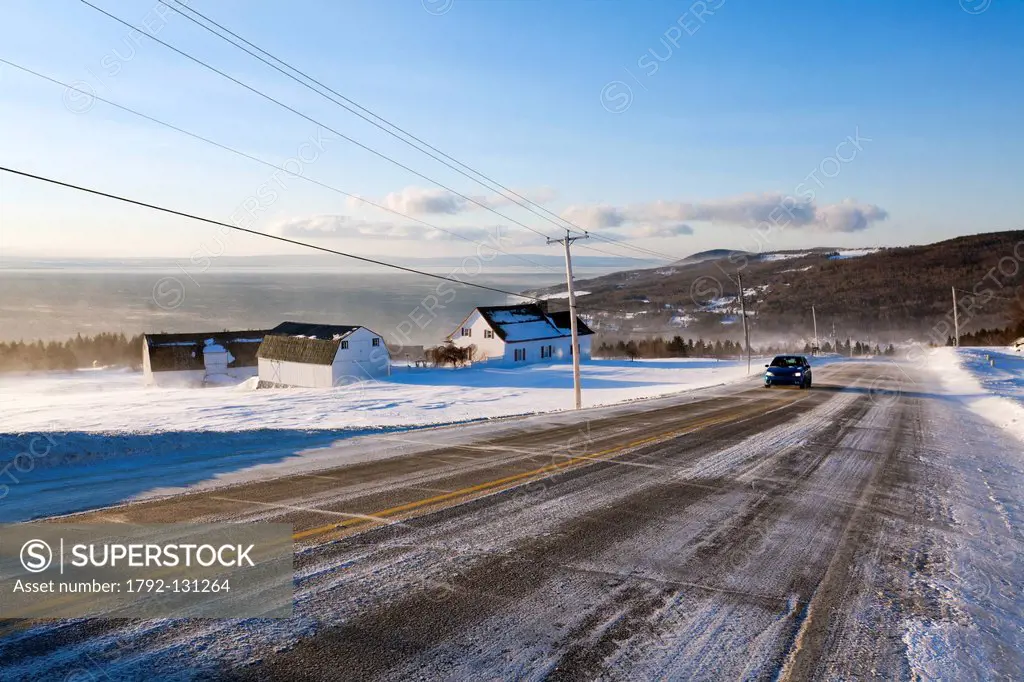 Canada, Quebec province, Charlevoix, St Irenee, the St Lawrence River Road snow covered field and traditional farm, road and winter driving
