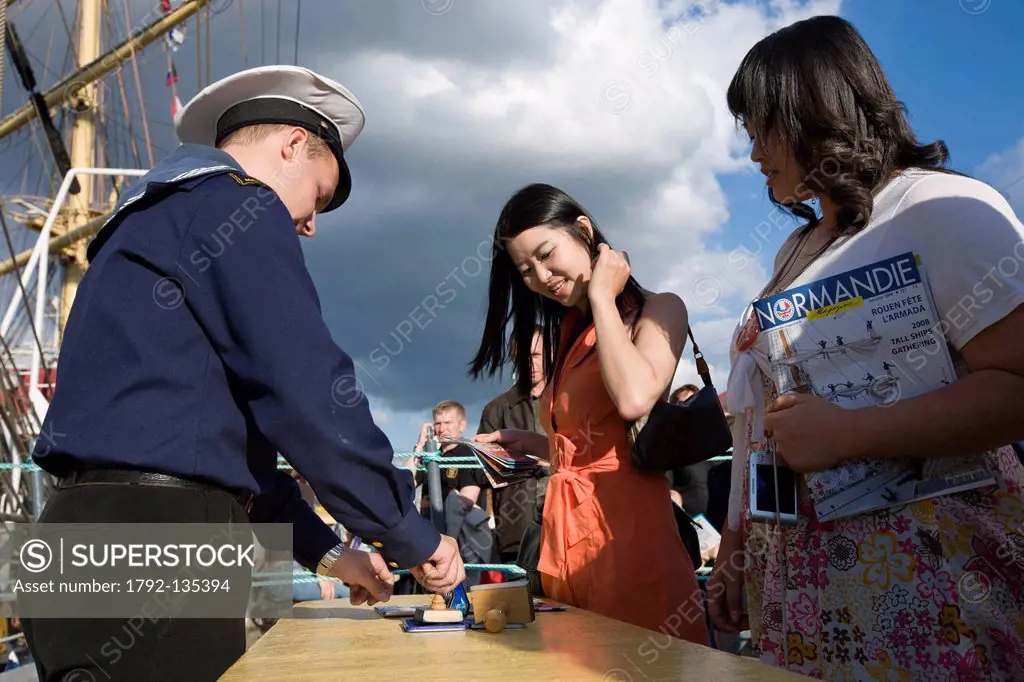 France, Seine Maritime, Rouen, Armada 2008, two young female Korean tourists receiving a Mir tall ship stamp from a Russian sailor
