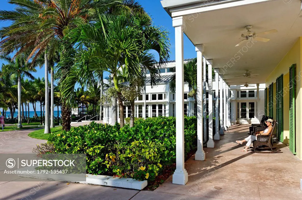 Bahamas, Grand Bahama Island, Freeport, Grand Lucayan Radisson, colonnial type architecture, a young woman in a chair under the arches of the terrace ...