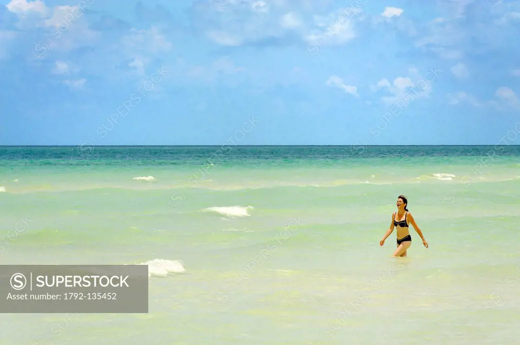 Bahamas, Grand Bahama Island, Freetown, young woman walking in water on a beach with clear waters