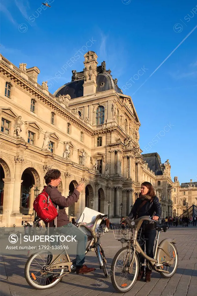 France, Paris, tourists on a bicycle in the Cour Napoleon of the Musee du Louvre
