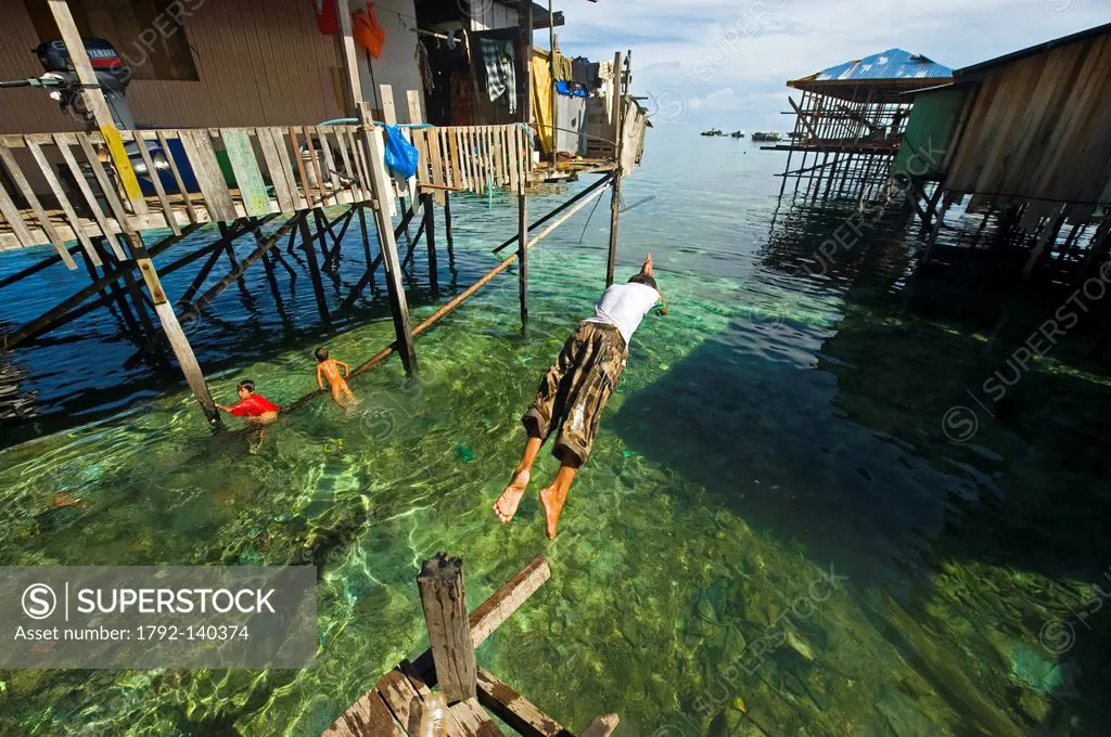 Malaysia, Borneo, Sabah State, Semporna, Mabul, Dayak Lau sea gypsies playing and jumping into the green water