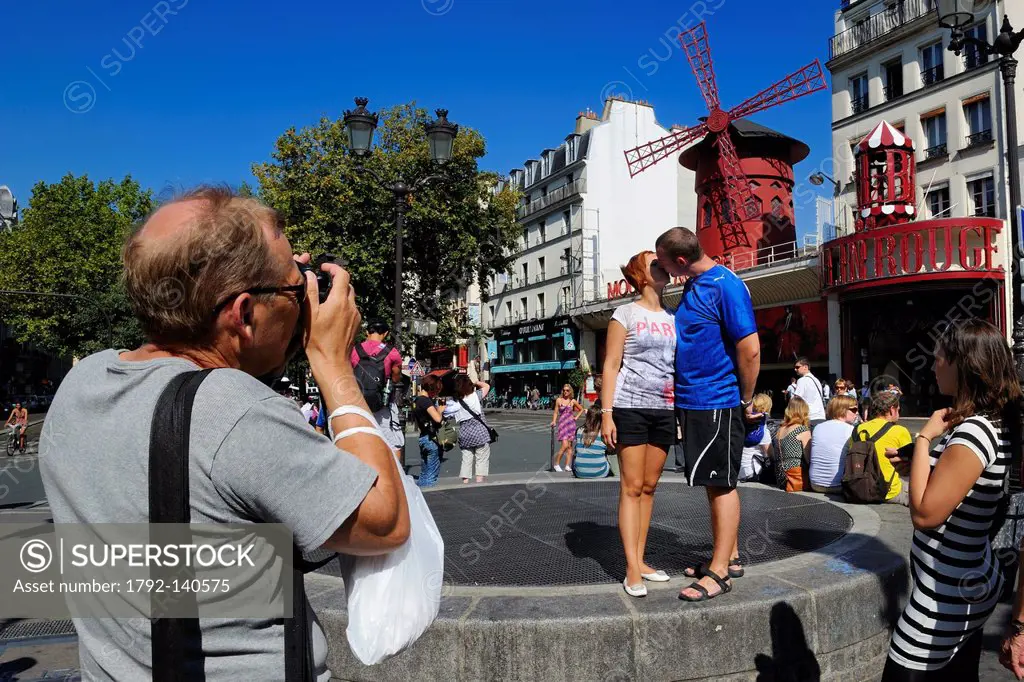 France, Paris, Place Blanche, a tourist couple in love having their picture taken in front of the Moulin Rouge Moulin Rouge registered trademark, requ...