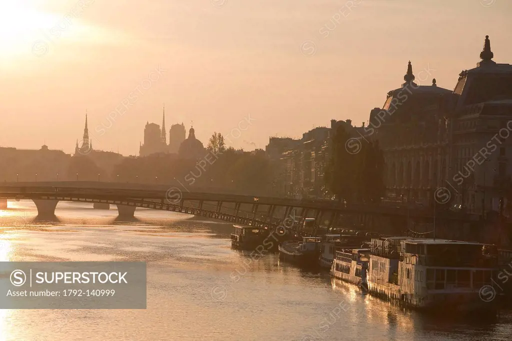 France, Paris, sunrise on the riverbanks of the Seine, listed as World Heritage by UNESCO, bacllighting over the Passerelle des Tuileries and Notre_Da...