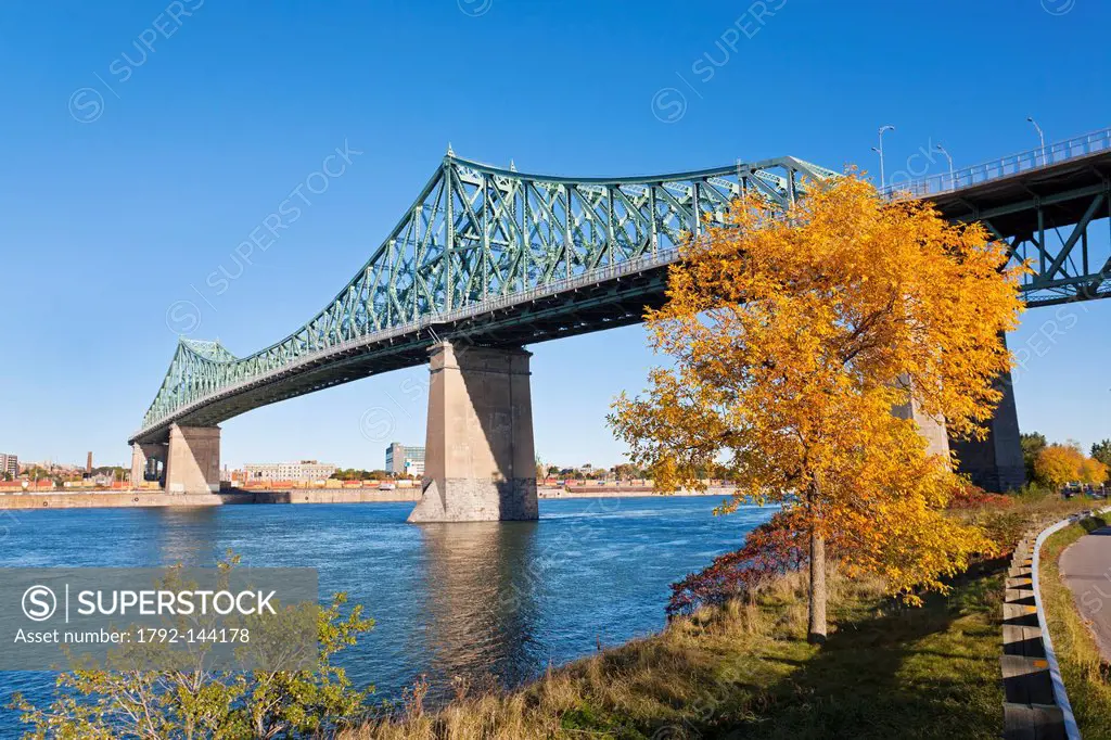 Canada, Quebec Province, Montreal, Jacques Cartier Bridge from the banks of the St. Lawrence River on Ile Sainte Helene, tree in Autumn colors