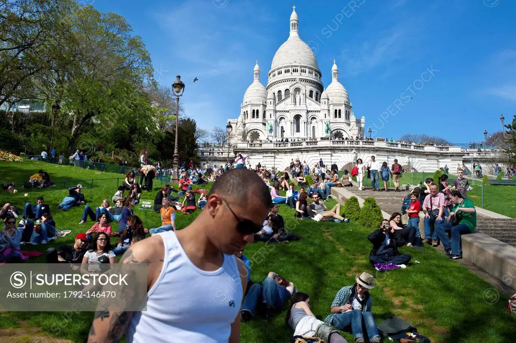 France, Paris, Montmartre, relaxing on the slopes of the Butte Montmartre in spring at the foot of the Sacree Cur basilica